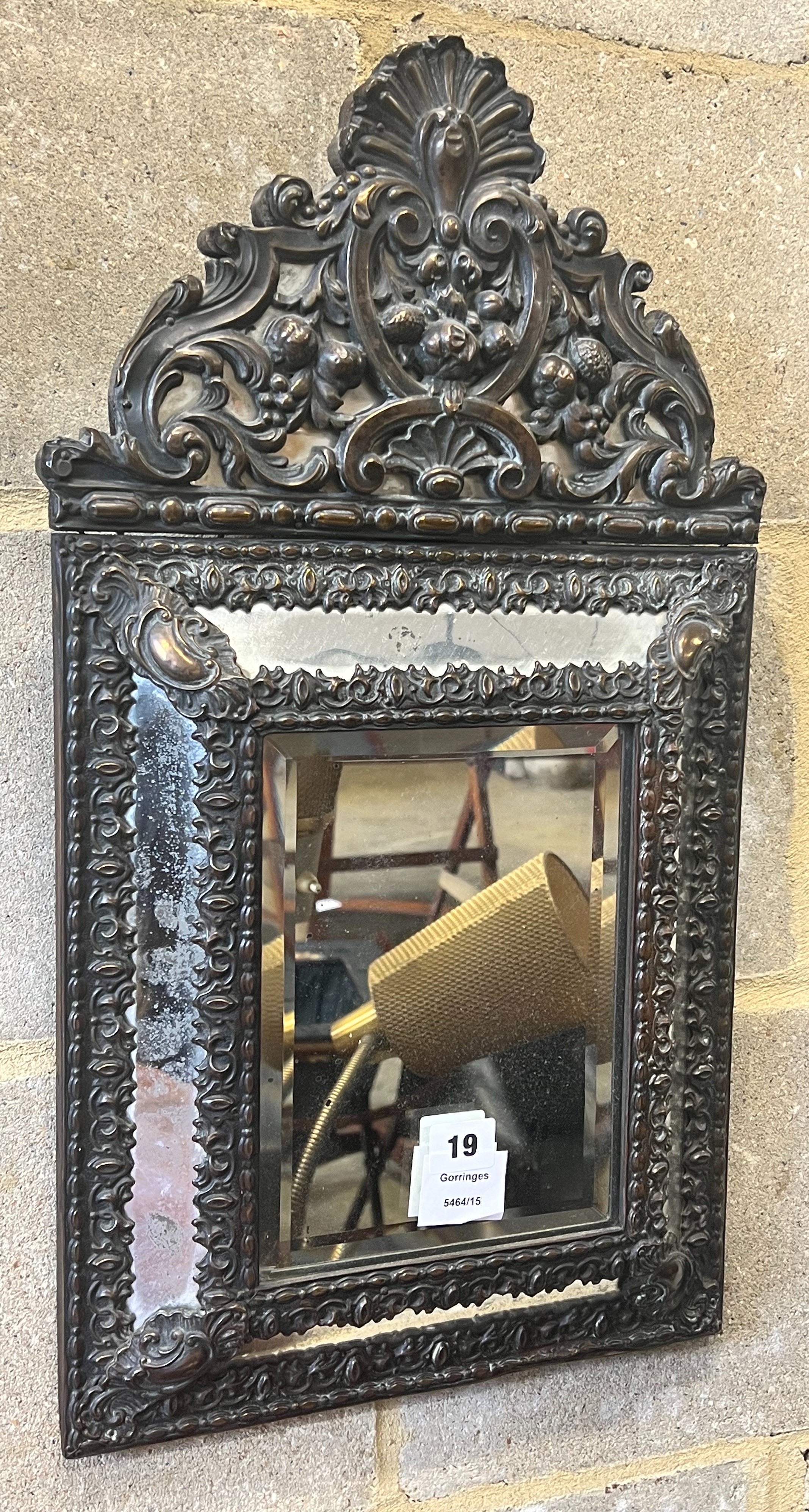 A Dutch brass framed cushion wall mirror, with ornate arched cresting, pierced and repousse with birds, scrollwork and shell surmount, width 33cm height 58cm